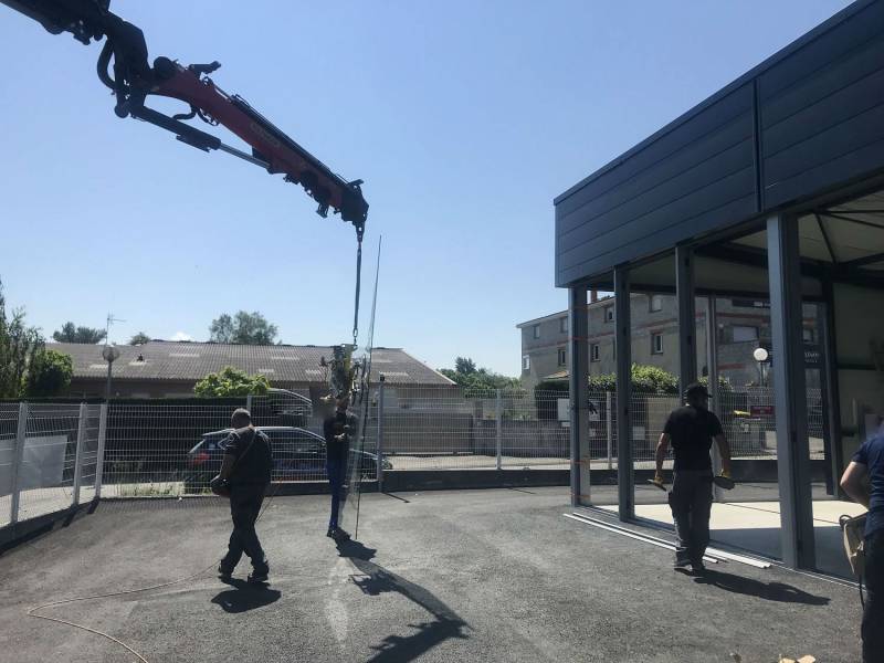 Mise en place des vitrages par camion grue sur vitrine de magasin en cours de réalisation