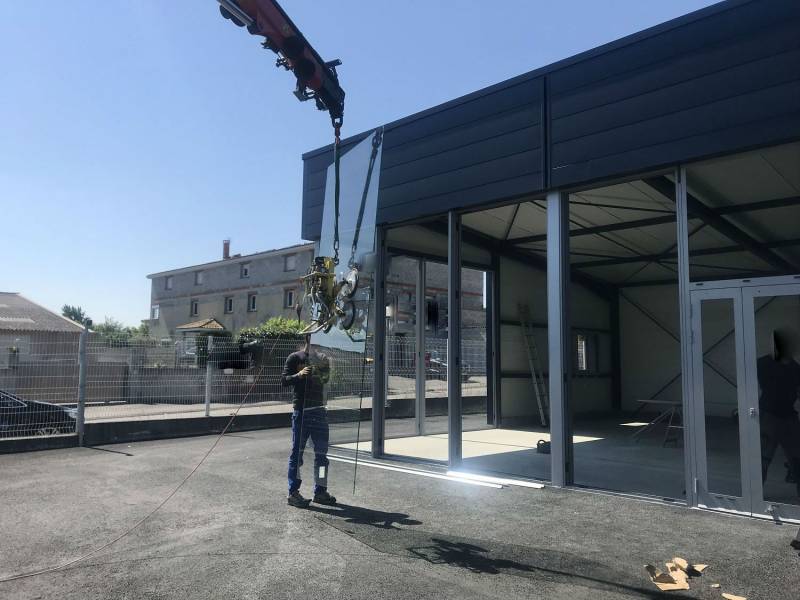 Mise en place des vitrages par camion grue sur vitrine de magasin en cours de réalisation